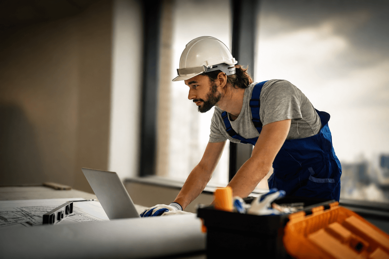 Technician reviewing project plans on a laptop with tools nearby