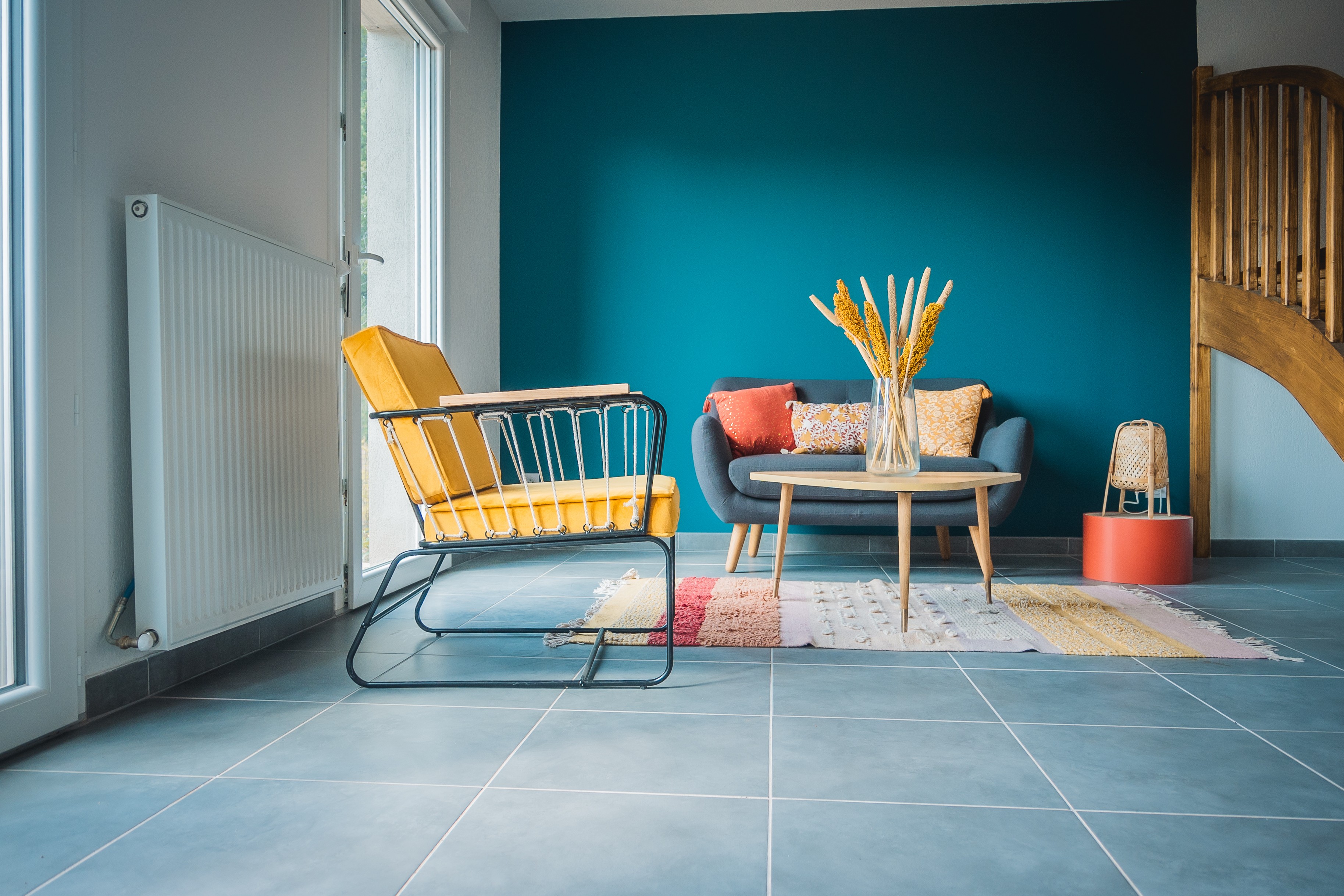Living room interior with teal accent wall and yellow chair