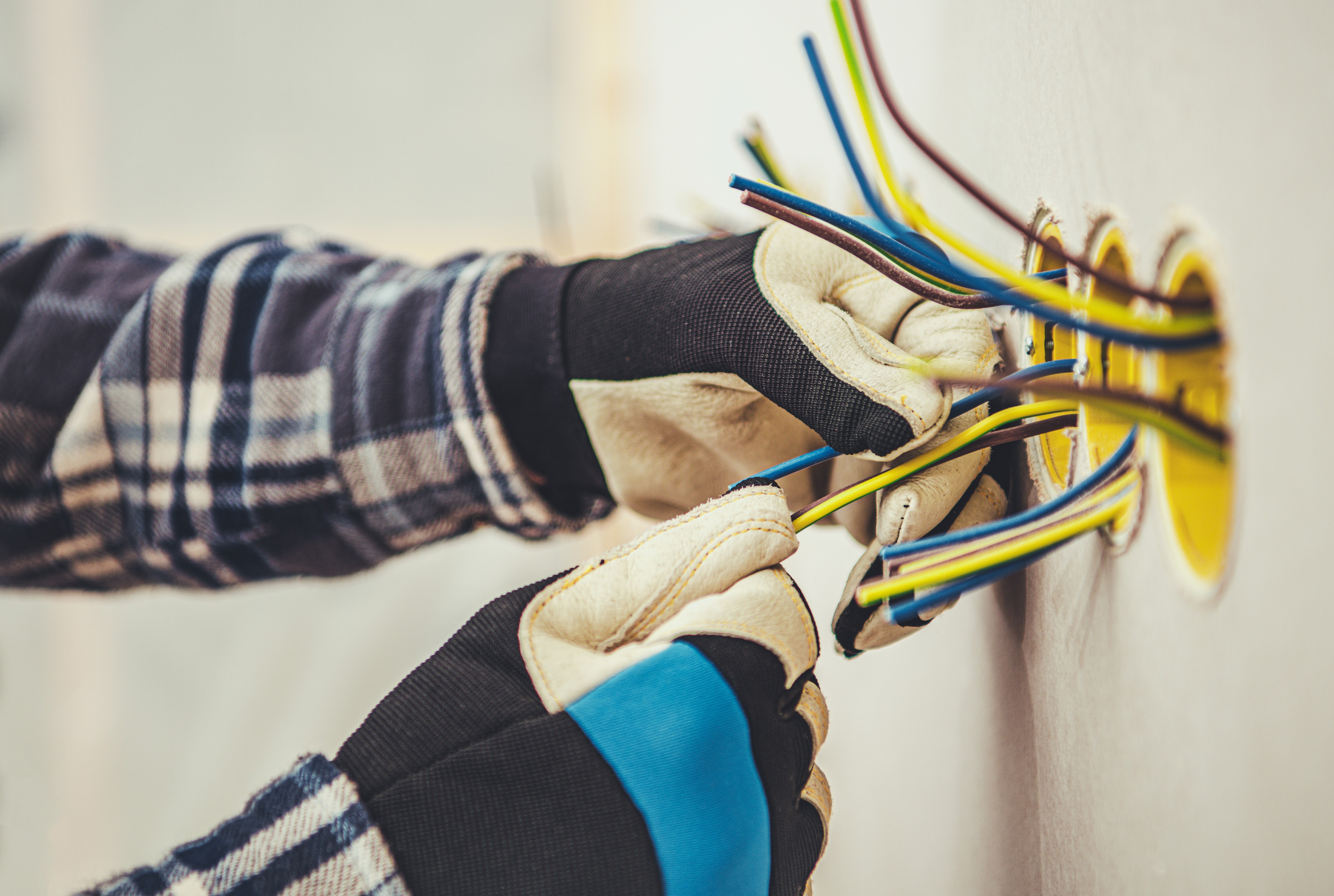 Close-up of hands connecting wires to an electrical outlet