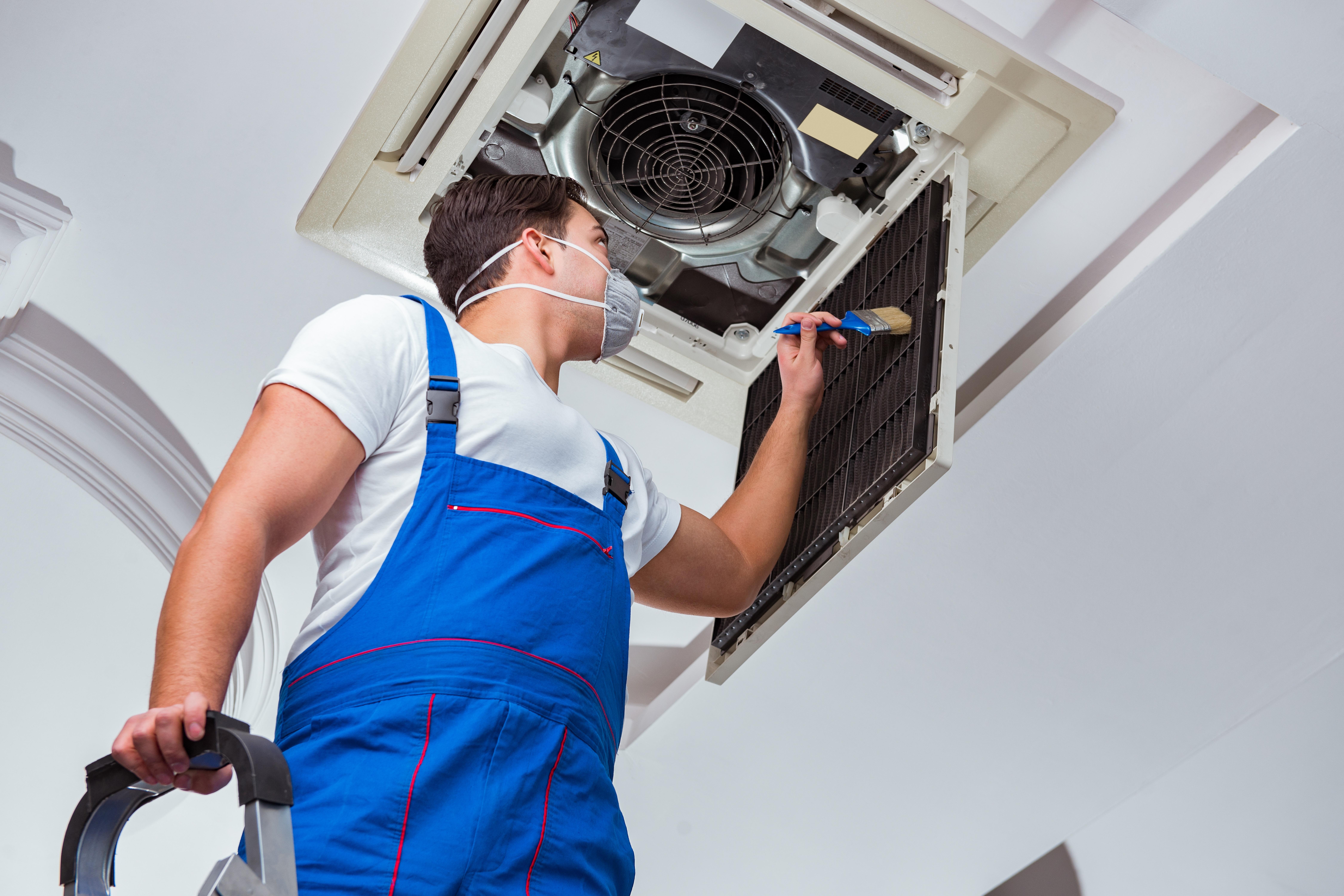 Technician inspecting an overhead air conditioning unit