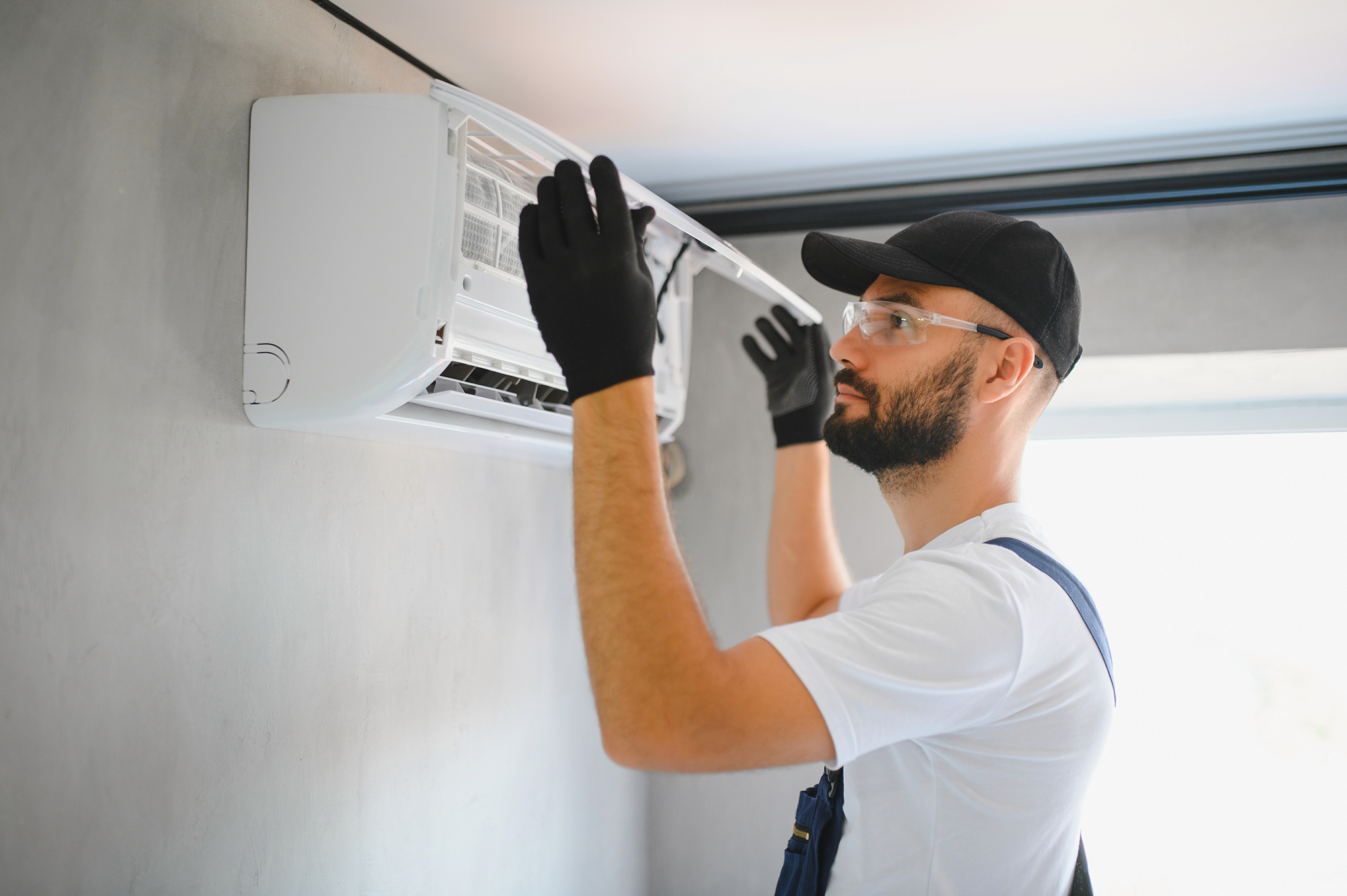 Technician adjusting an indoor wall-mounted air conditioning unit