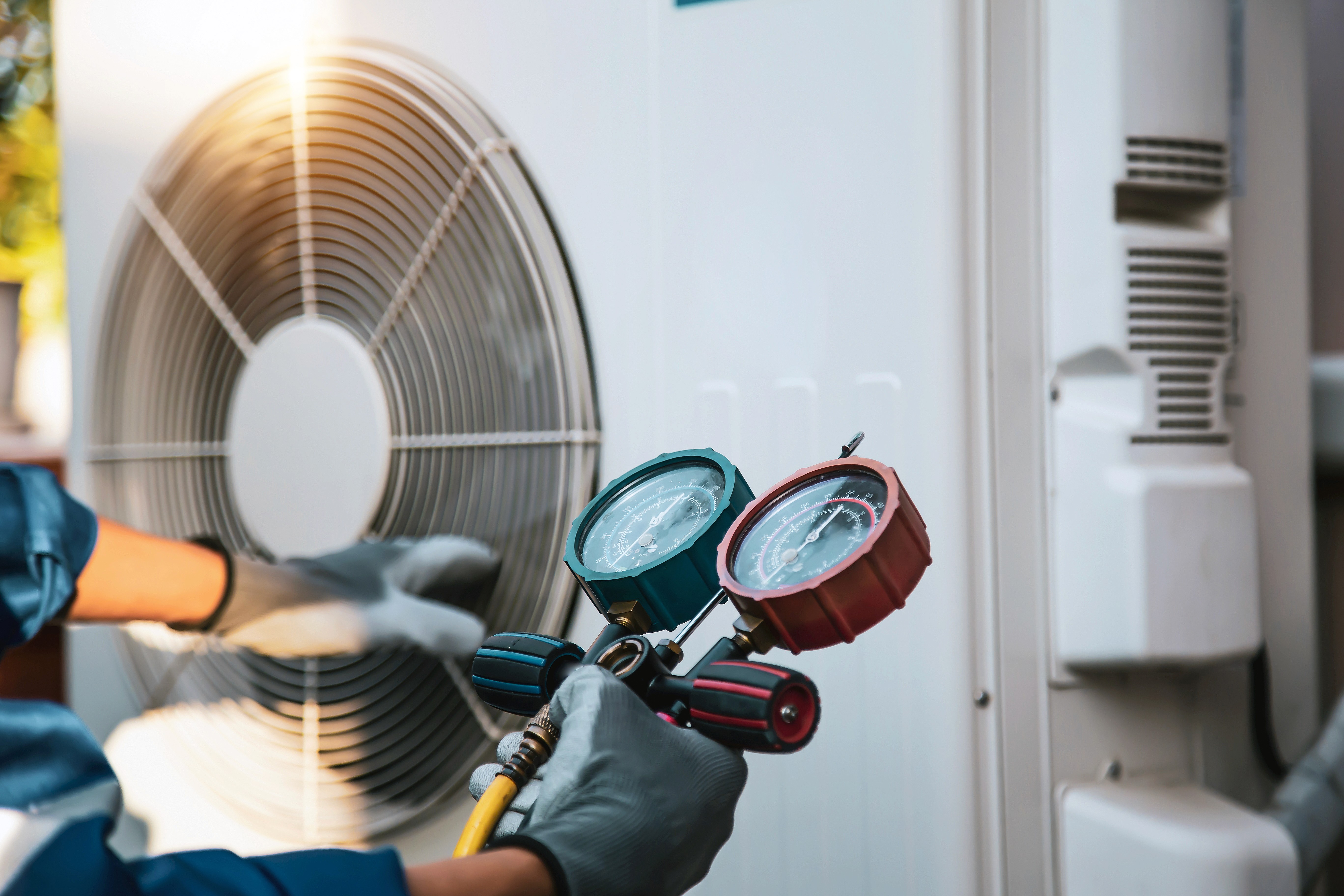 Technician using pressure gauges to service an outdoor AC unit