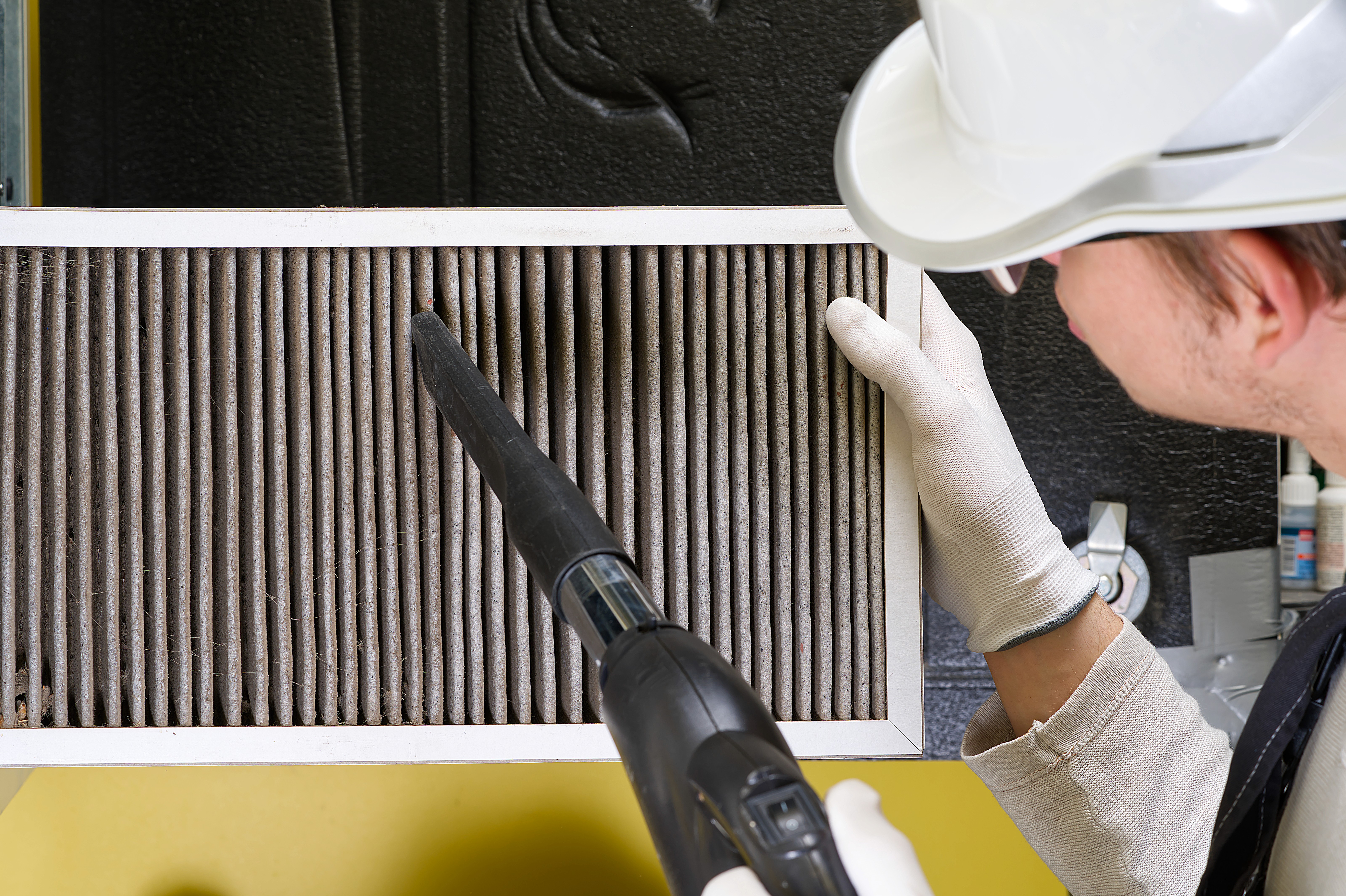 Technician vacuuming dust from an air conditioning filter